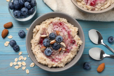 Tasty oatmeal porridge with toppings served on light blue wooden table, flat lay Photo of Tasty oatmeal porridge with toppings served on light blue wooden table, flat lay