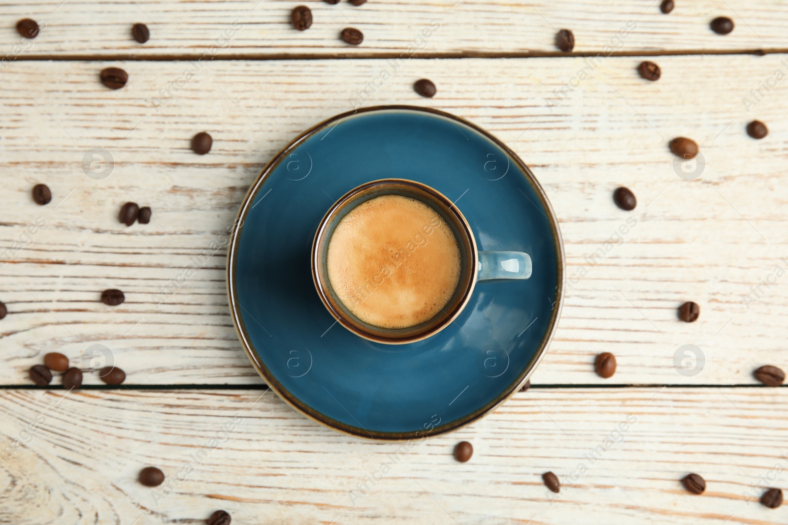 Cup of hot aromatic espresso and roasted beans on white wooden table, flat lay Photo of Cup of hot aromatic espresso and roasted beans on white wooden table, flat lay