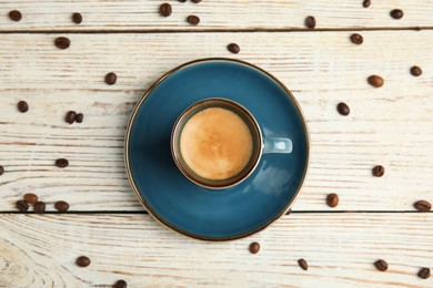 Cup of hot aromatic espresso and roasted beans on white wooden table, flat lay Photo of Cup of hot aromatic espresso and roasted beans on white wooden table, flat lay