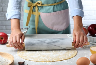 Woman rolling dough for apple pie at light grey table, closeup Photo of Woman rolling dough for apple pie at light grey table, closeup