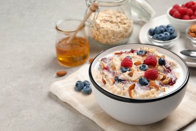 Tasty oatmeal porridge with toppings served on grey table. Space for text Photo of Tasty oatmeal porridge with toppings served on grey table. Space for text