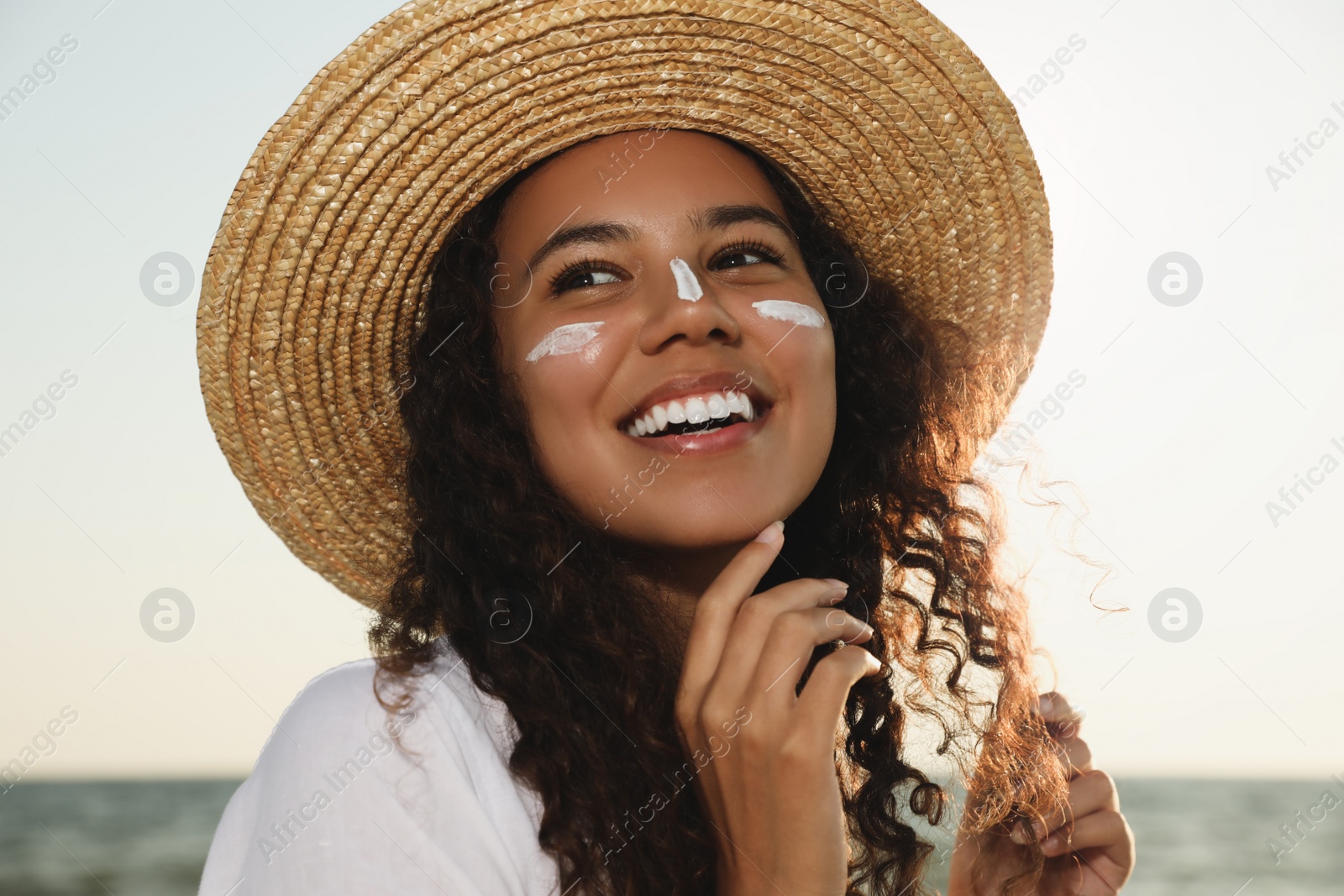Happy African American woman with sun protection cream on face near sea Photo of Happy African American woman with sun protection cream on face near sea