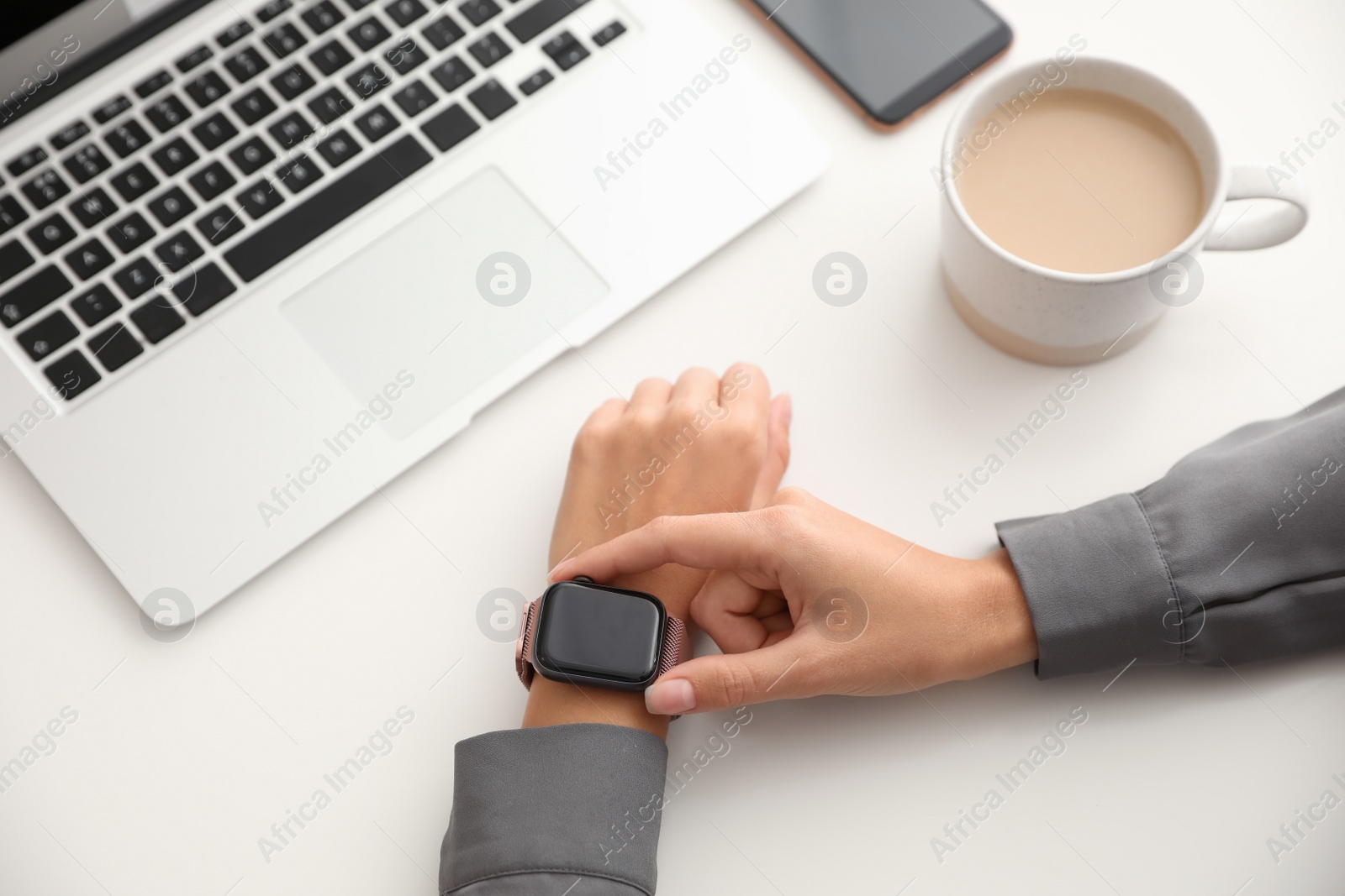 Woman checking stylish smart watch at table, closeup Image of Woman checking stylish smart watch at table, closeup
