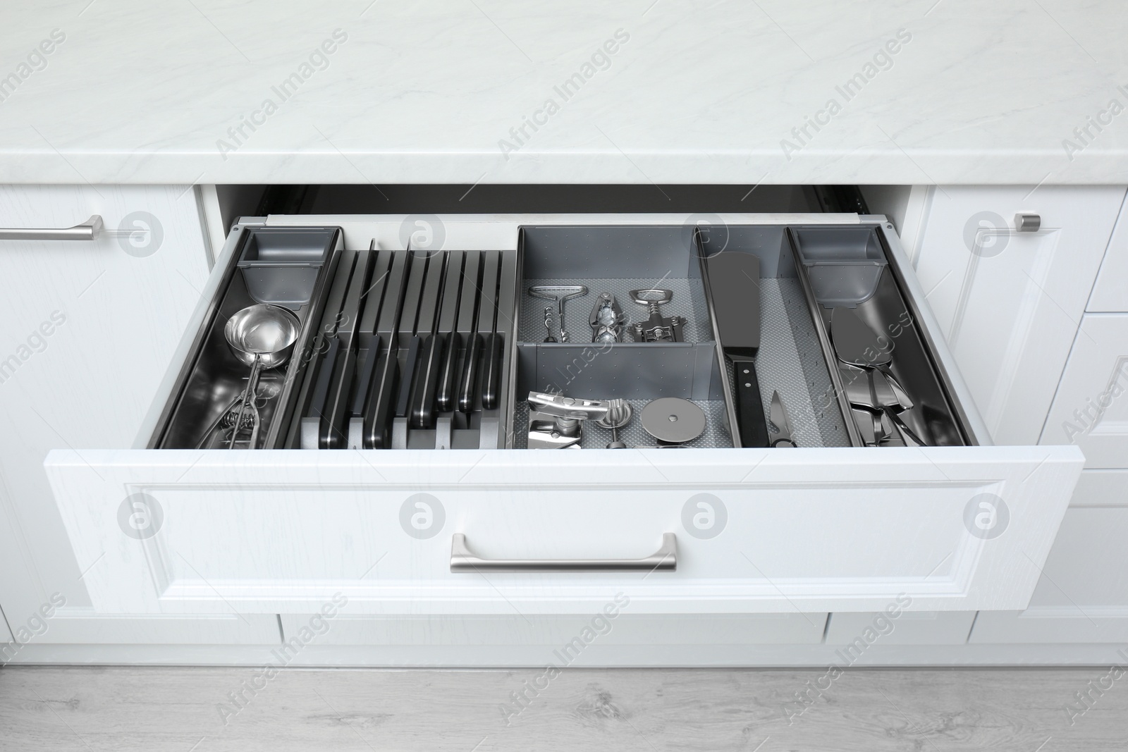 Open drawer with stainless steel utensil set. Order in kitchen Photo of Open drawer with stainless steel utensil set. Order in kitchen
