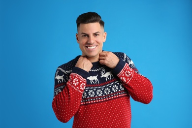 Photo of Handsome man in Christmas sweater on blue background