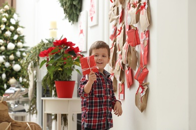 Cute little boy taking gift from Advent calendar at home. Christmas tradition Photo of Cute little boy taking gift from Advent calendar at home. Christmas tradition
