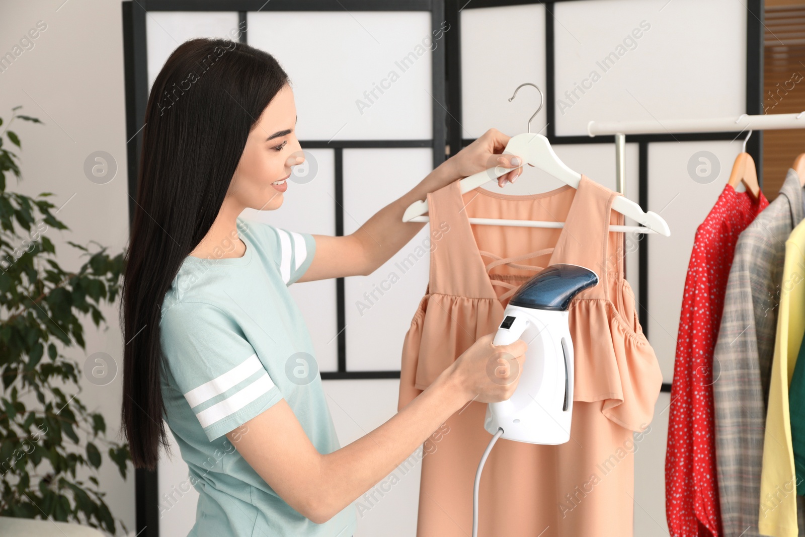 Woman steaming dress on hanger at home Photo of Woman steaming dress on hanger at home