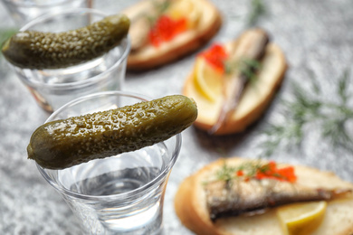 Cold Russian vodka with pickles on grey table, closeup Photo of Cold Russian vodka with pickles on grey table, closeup