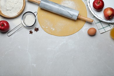 Flat lay composition with raw dough and ingredients on light grey table, space for text. Baking apple pie Photo of Flat lay composition with raw dough and ingredients on light grey table, space for text. Baking apple pie
