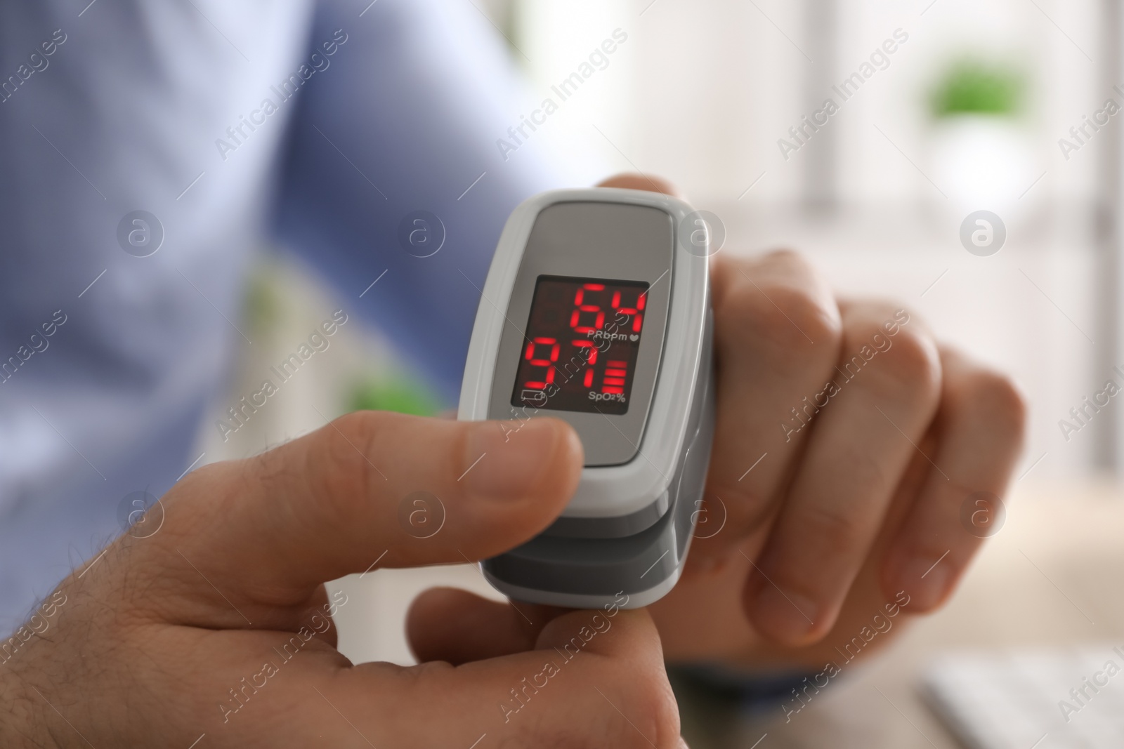 Man measuring oxygen level with modern fingertip pulse oximeter at workplace, closeup Photo of Man measuring oxygen level with modern fingertip pulse oximeter at workplace, closeup