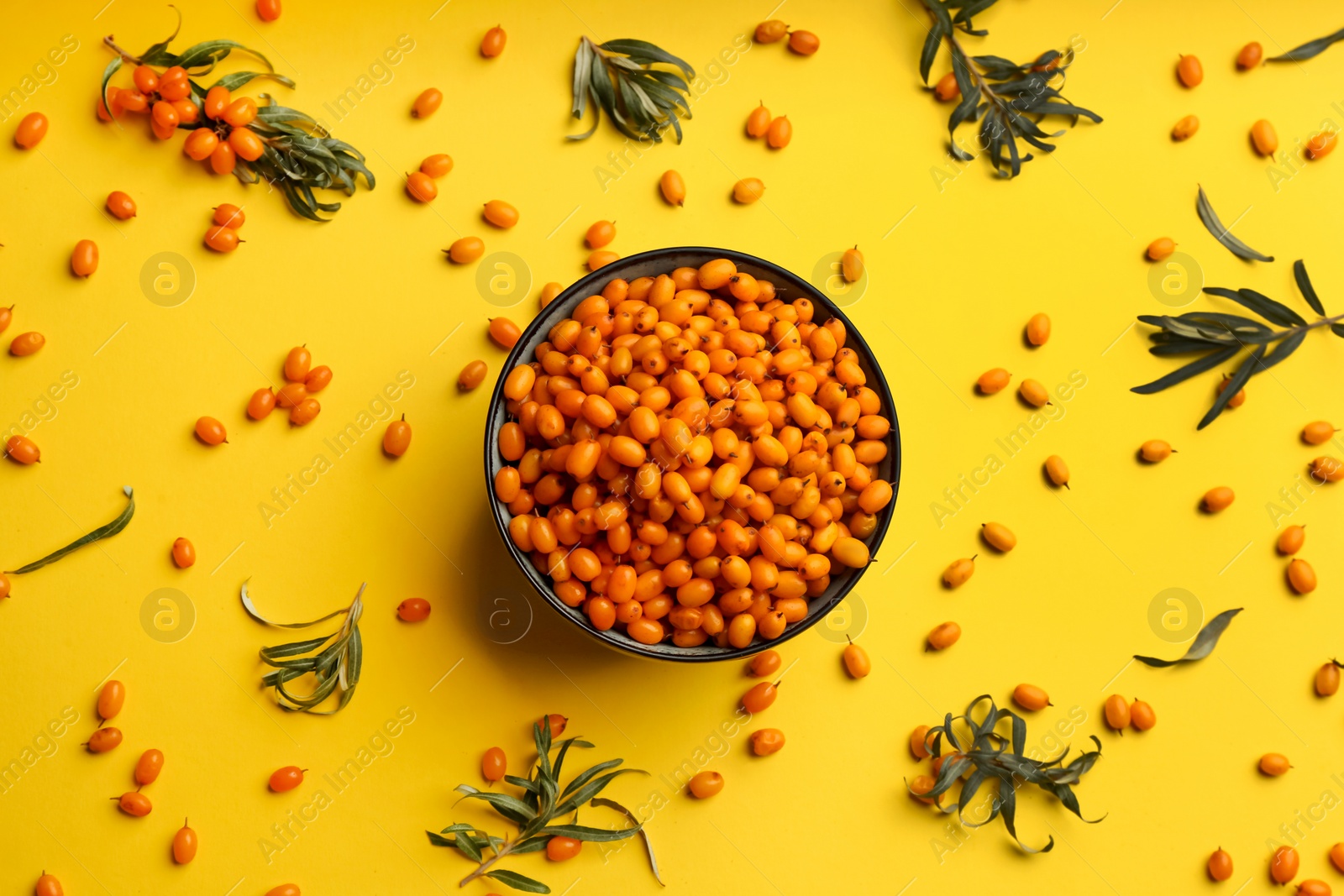 Fresh ripe sea buckthorn on yellow background, flat lay Photo of Fresh ripe sea buckthorn on yellow background, flat lay