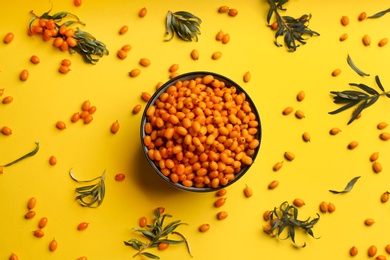 Fresh ripe sea buckthorn on yellow background, flat lay Photo of Fresh ripe sea buckthorn on yellow background, flat lay