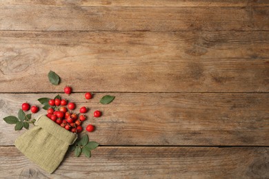 Ripe rose hip berries with green leaves on wooden table, flat lay. Space for text Photo of Ripe rose hip berries with green leaves on wooden table, flat lay. Space for text