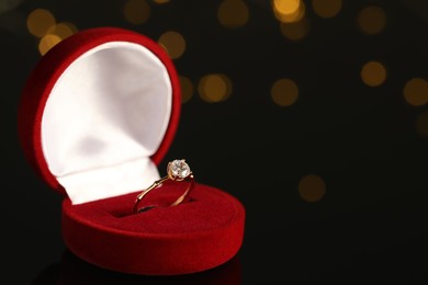 Beautiful engagement ring in red box against blurred festive lights, space for text Photo of Beautiful engagement ring in red box against blurred festive lights, space for text