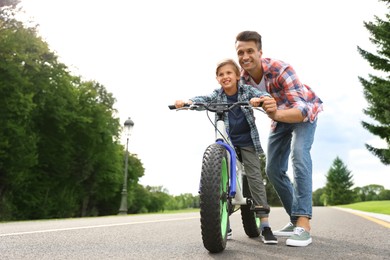 Dad teaching son to ride bicycle outdoors Image of Dad teaching son to ride bicycle outdoors