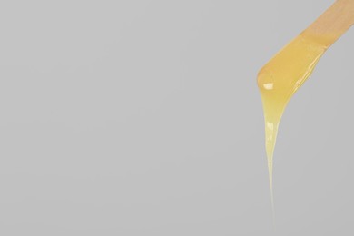 Wooden spatula with hot depilatory wax on light grey background. Space for text Photo of Wooden spatula with hot depilatory wax on light grey background. Space for text