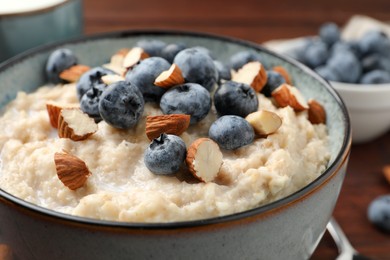 Tasty oatmeal porridge with blueberries and almond nuts in bowl on table, closeup Photo of Tasty oatmeal porridge with blueberries and almond nuts in bowl on table, closeup