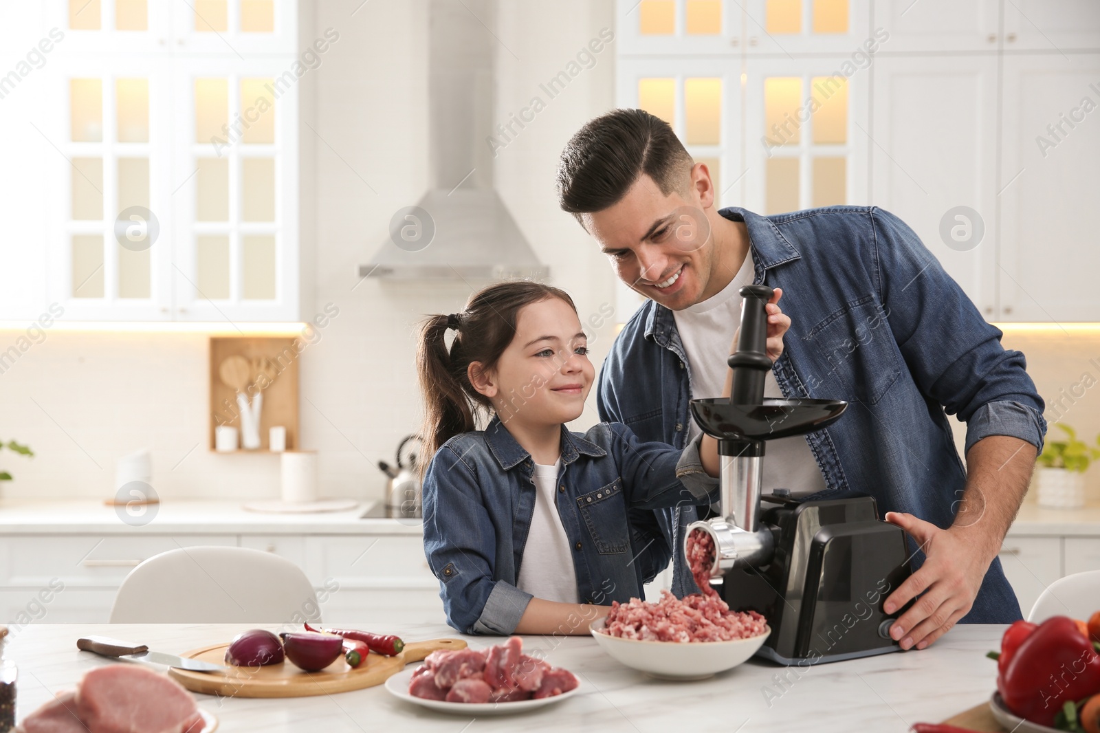 Father and daughter using modern meat grinder in kitchen. Space for text Photo of Father and daughter using modern meat grinder in kitchen. Space for text