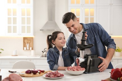 Father and daughter using modern meat grinder in kitchen. Space for text Photo of Father and daughter using modern meat grinder in kitchen. Space for text