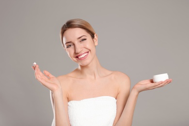 Young woman with jar of body cream on color background Photo of Young woman with jar of body cream on color background