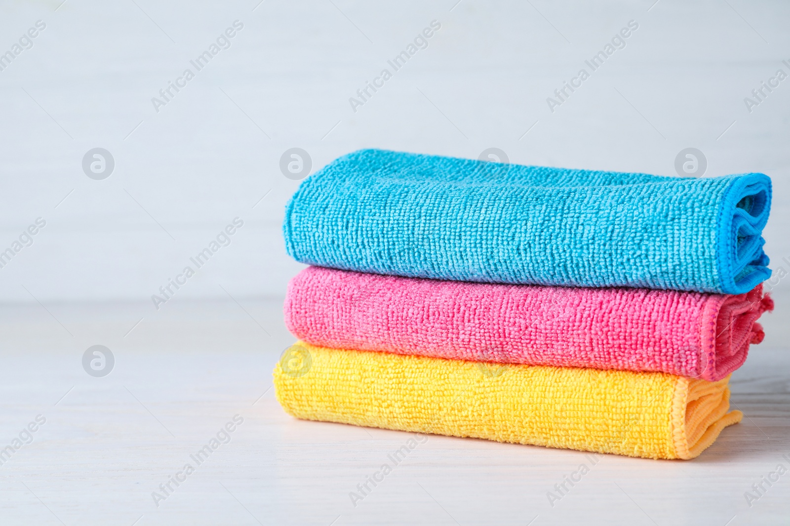 Stack of colorful microfiber cloths on white table, space for text Photo of Stack of colorful microfiber cloths on white table, space for text