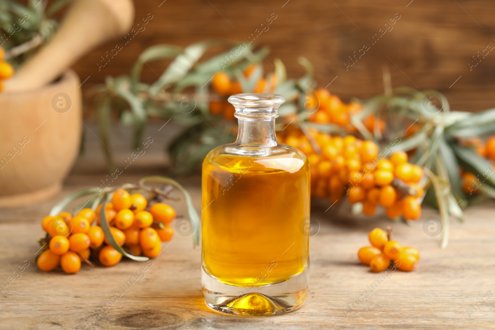 Natural sea buckthorn oil and fresh berries on wooden table Photo of Natural sea buckthorn oil and fresh berries on wooden table