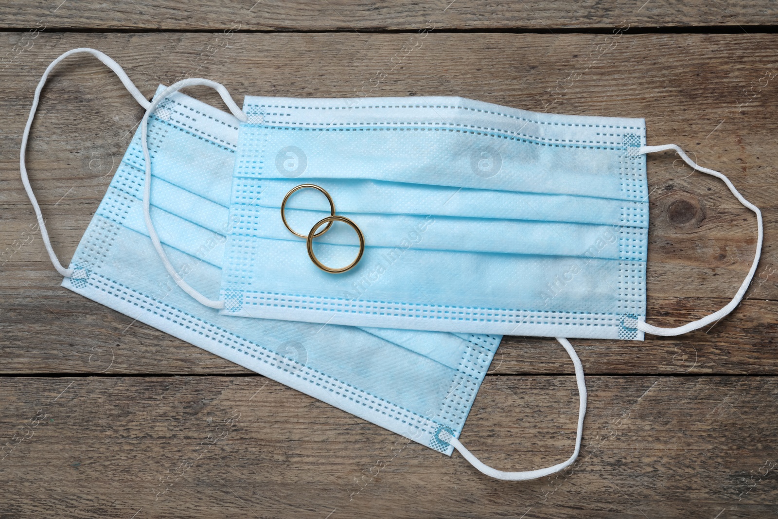 Protective masks and wedding rings on wooden table, flat lay. Divorce during coronavirus quarantine Photo of Protective masks and wedding rings on wooden table, flat lay. Divorce during coronavirus quarantine