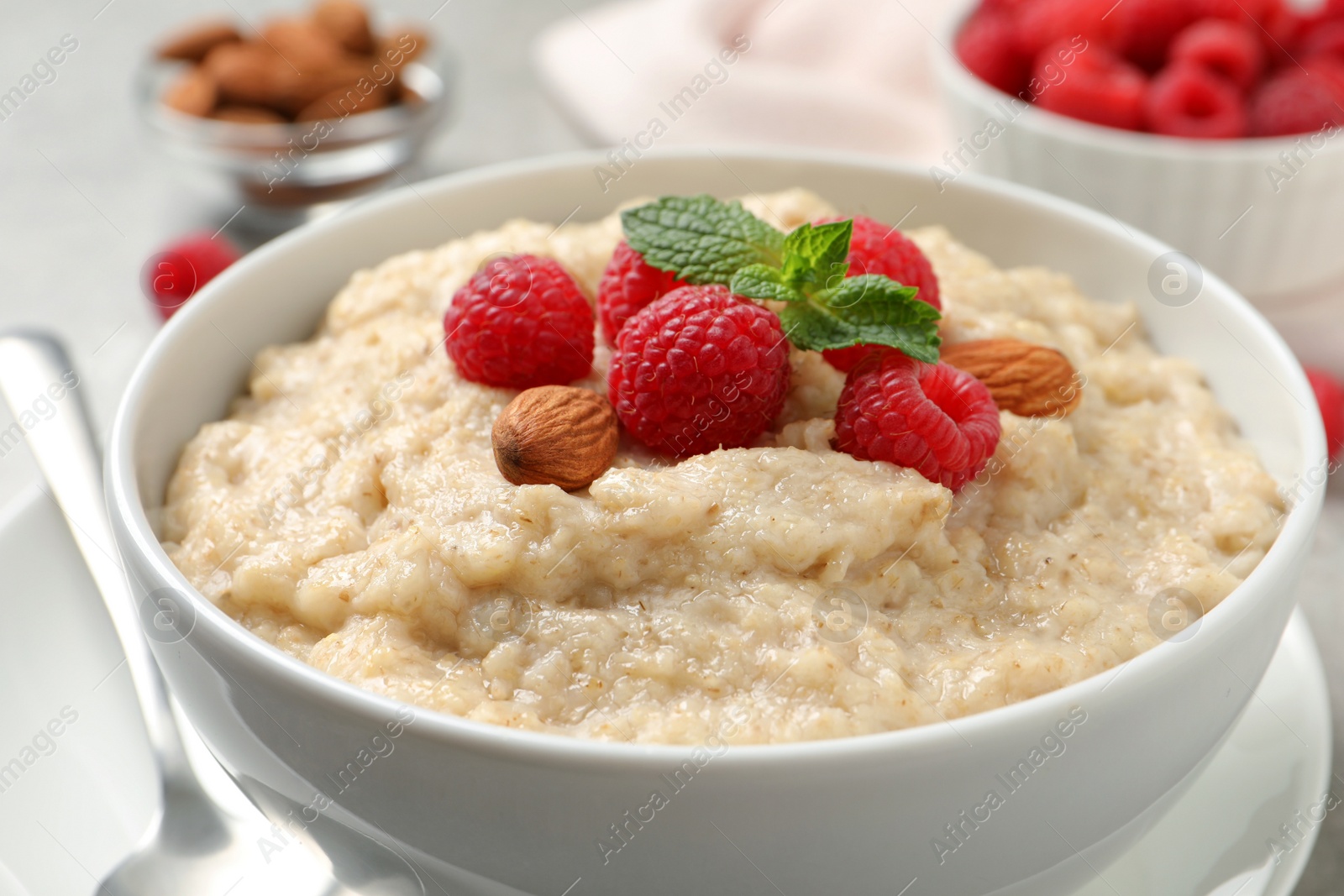 Tasty oatmeal porridge with raspberries and almond nuts in bowl on table, closeup Photo of Tasty oatmeal porridge with raspberries and almond nuts in bowl on table, closeup
