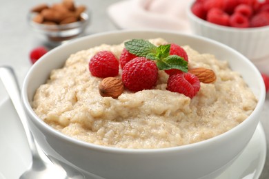 Tasty oatmeal porridge with raspberries and almond nuts in bowl on table, closeup Photo of Tasty oatmeal porridge with raspberries and almond nuts in bowl on table, closeup