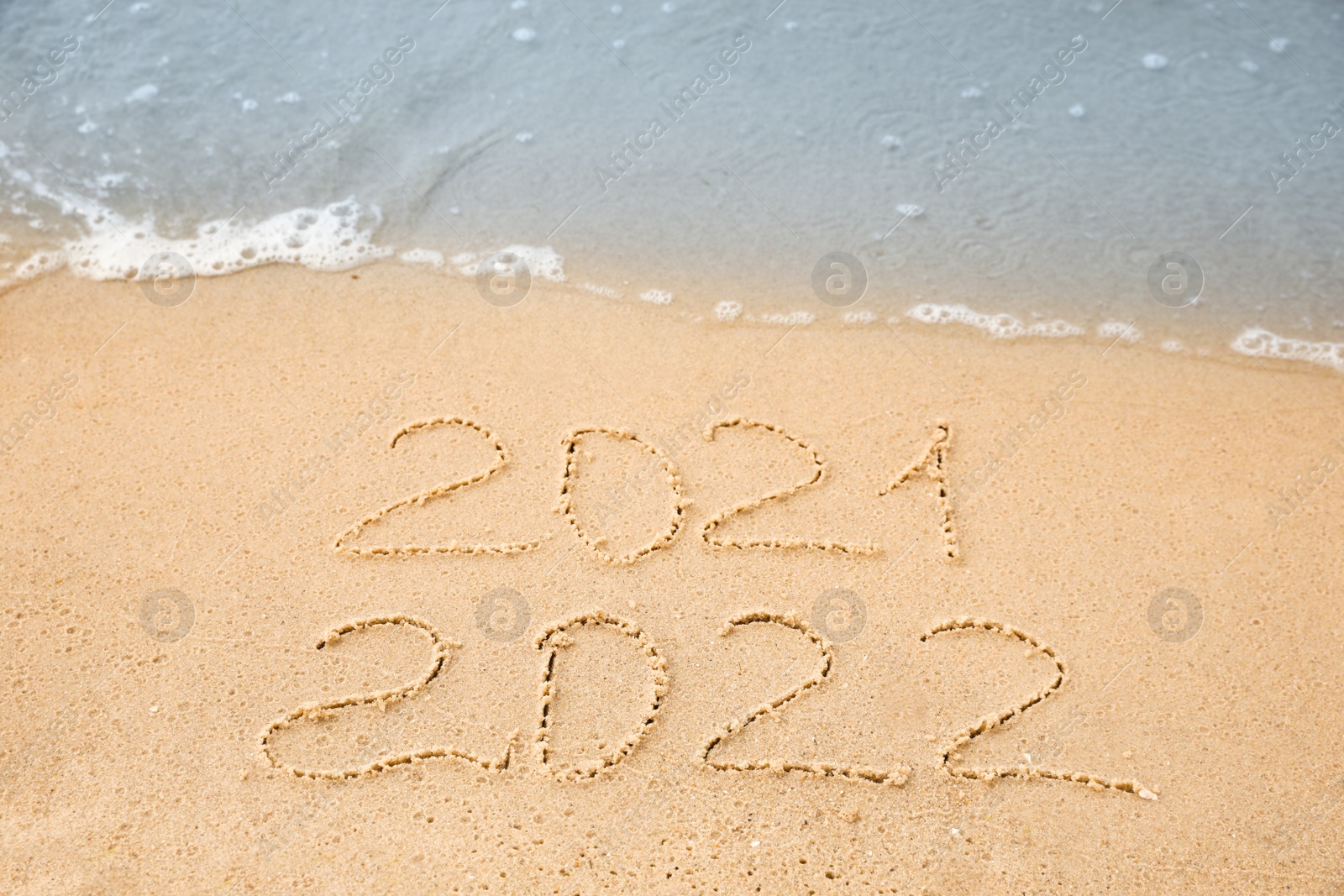 Dates written on sandy beach. 2021 washed by sea wave as New 2022 Year coming Photo of Dates written on sandy beach. 2021 washed by sea wave as New 2022 Year coming