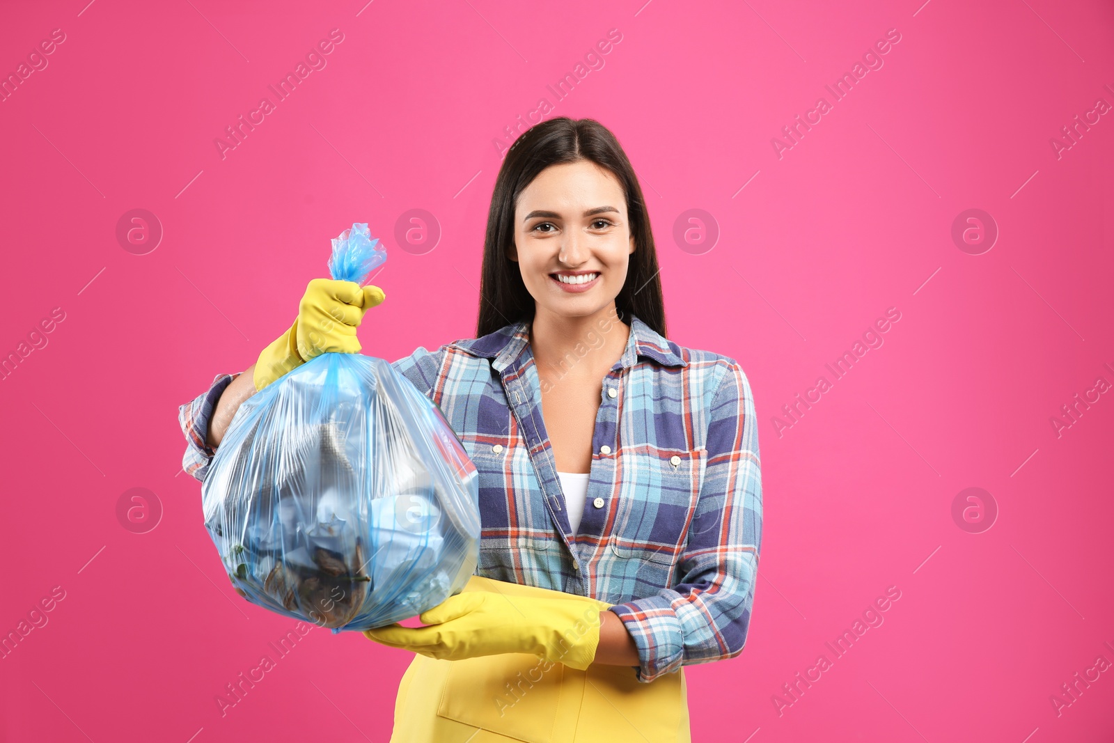 Woman holding full garbage bag on pink background Photo of Woman holding full garbage bag on pink background
