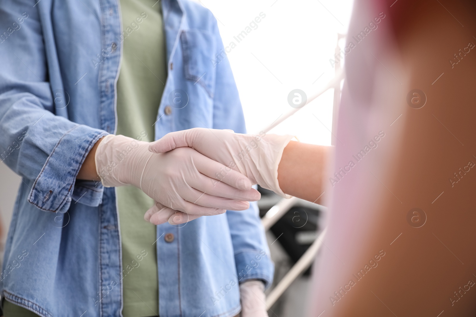 People in white medical gloves shaking hands on blurred background, closeup Photo of People in white medical gloves shaking hands on blurred background, closeup