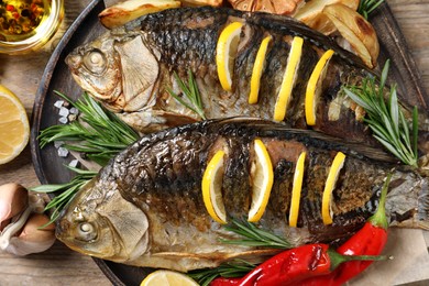 Tasty homemade roasted crucian carps served on wooden table, flat lay. River fish Photo of Tasty homemade roasted crucian carps served on wooden table, flat lay. River fish