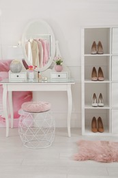 Stylish dressing room interior with shoes on shelving unit and table Photo of Stylish dressing room interior with shoes on shelving unit and table