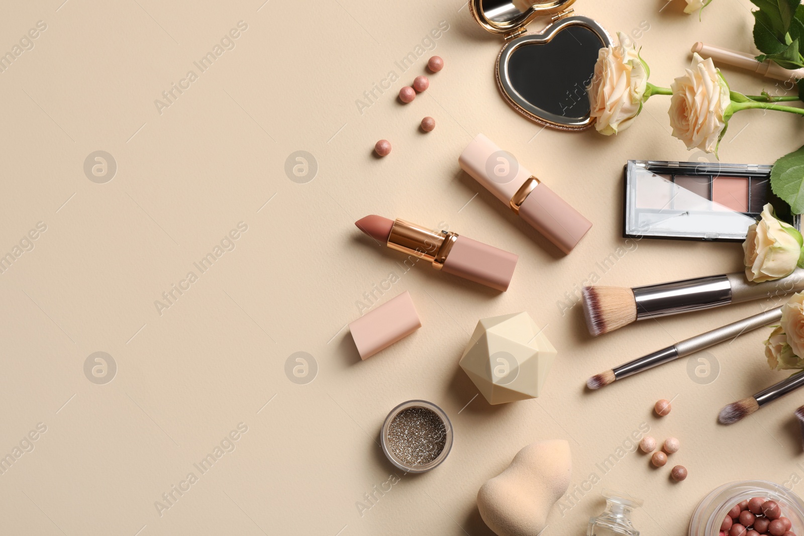 Flat lay composition with makeup products and beautiful roses on beige background, space for text Photo of Flat lay composition with makeup products and beautiful roses on beige background, space for text