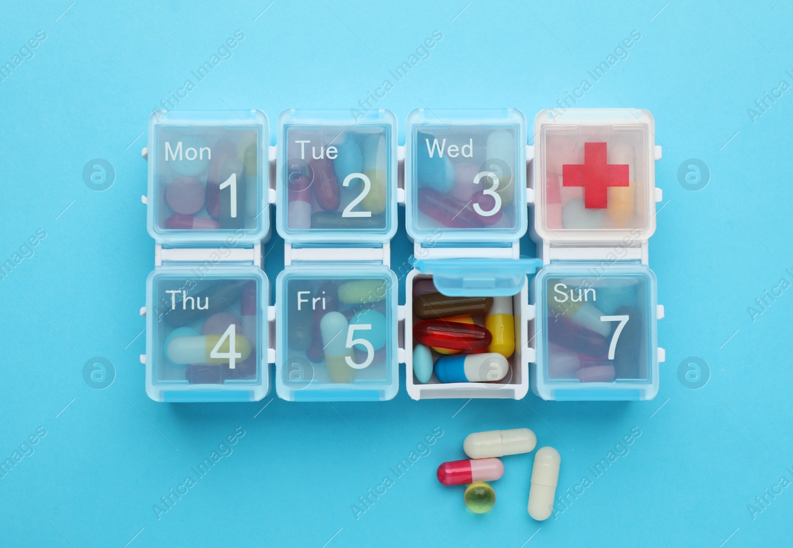 Pill box with medicaments on light blue background, flat lay Photo of Pill box with medicaments on light blue background, flat lay