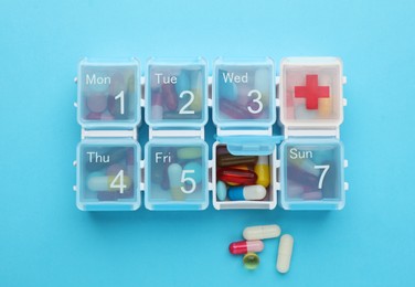 Pill box with medicaments on light blue background, flat lay Photo of Pill box with medicaments on light blue background, flat lay
