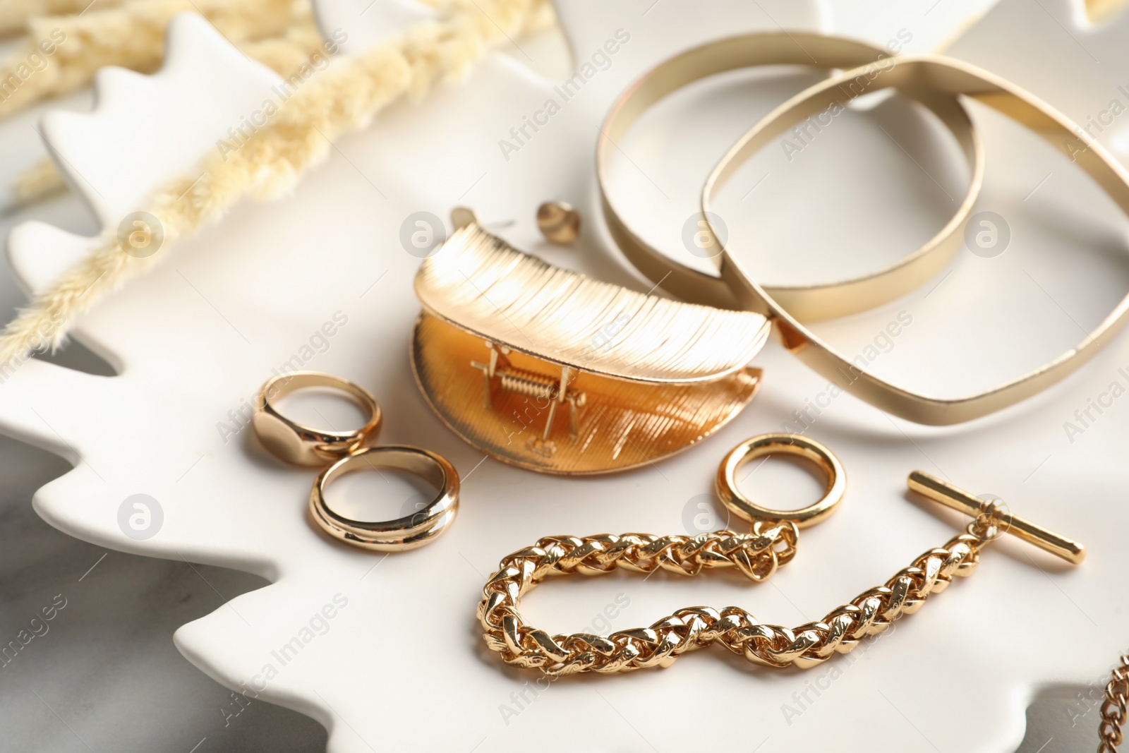 Plate with elegant bijouterie on white table, closeup Photo of Plate with elegant bijouterie on white table, closeup