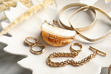 Plate with elegant bijouterie on white table, closeup Photo of Plate with elegant bijouterie on white table, closeup