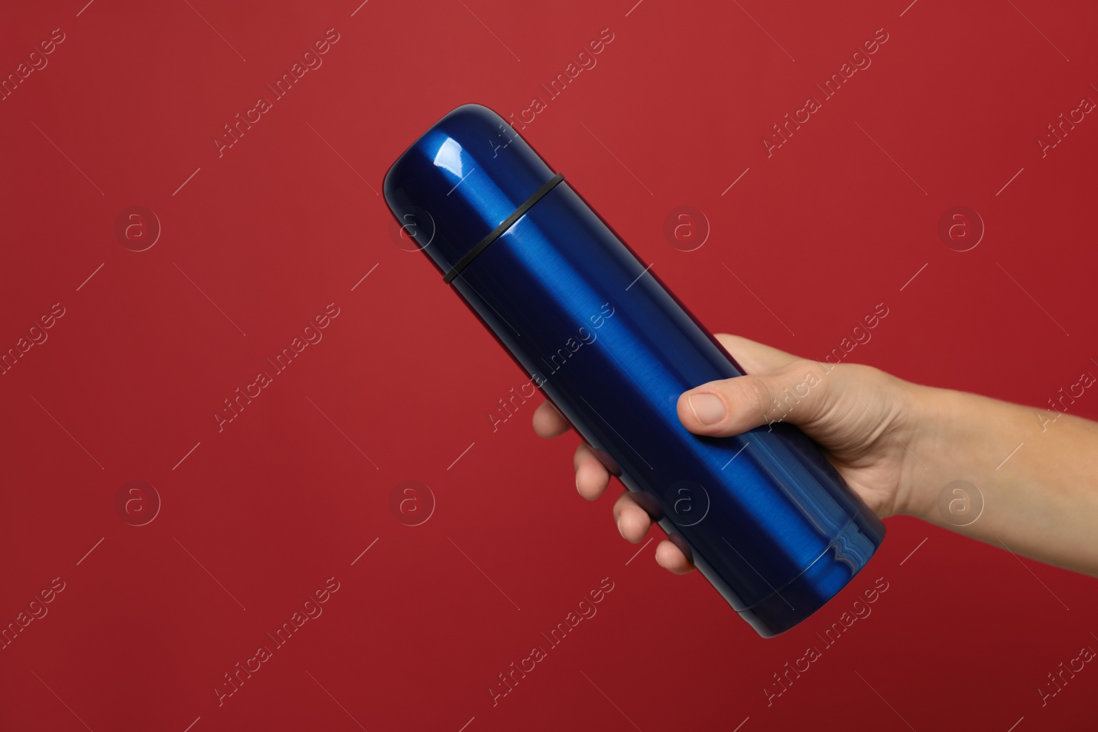 Woman holding modern blue thermos on red background, closeup Photo of Woman holding modern blue thermos on red background, closeup