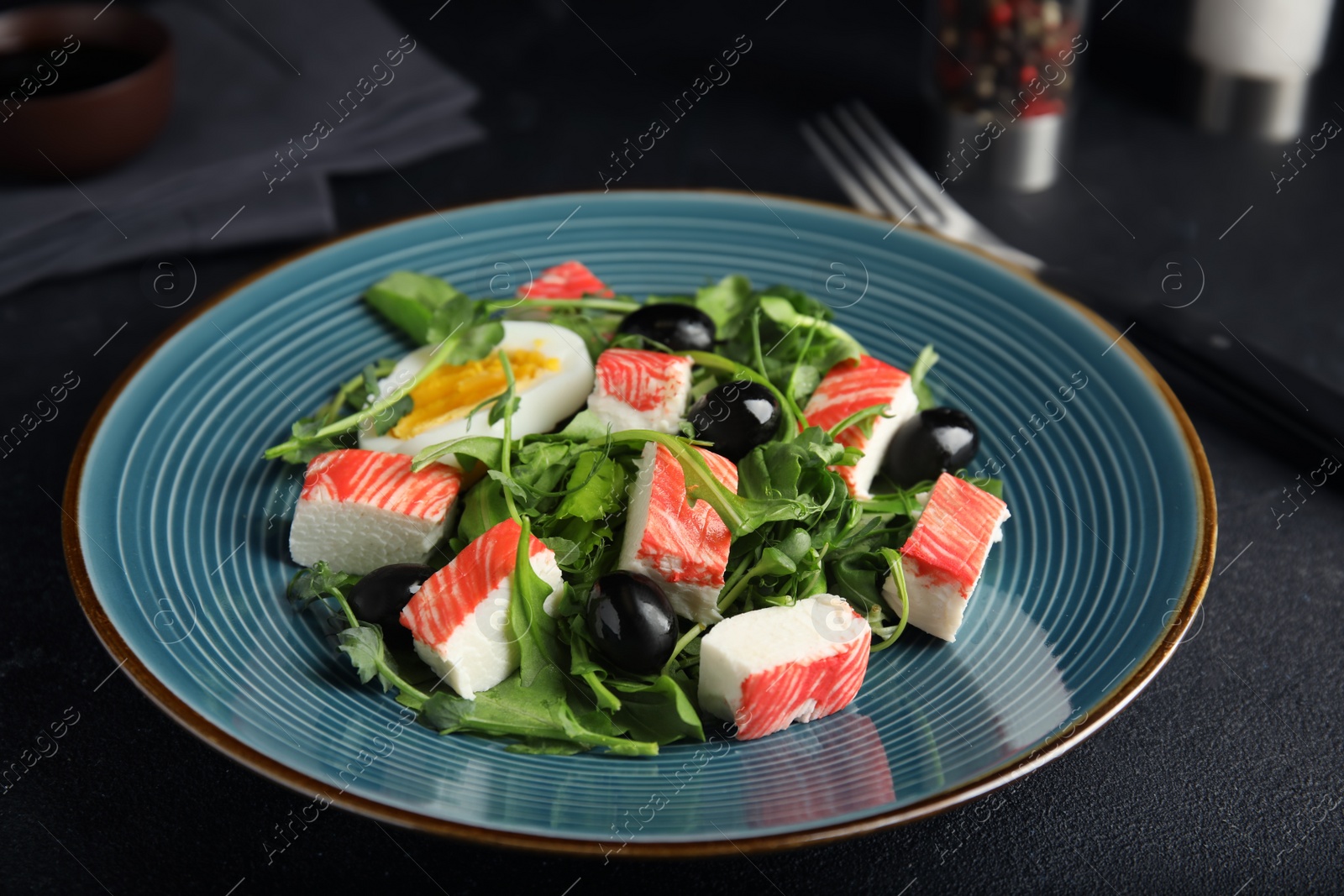 Delicious crab stick salad served on black table Photo of Delicious crab stick salad served on black table