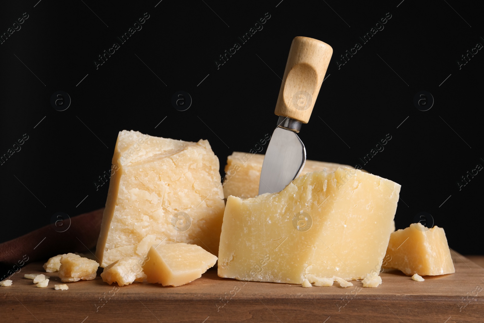Parmesan cheese with knife on wooden board, closeup Photo of Parmesan cheese with knife on wooden board, closeup