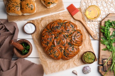 Traditional pampushka rolls with garlic and herbs on white wooden table, flat lay Photo of Traditional pampushka rolls with garlic and herbs on white wooden table, flat lay