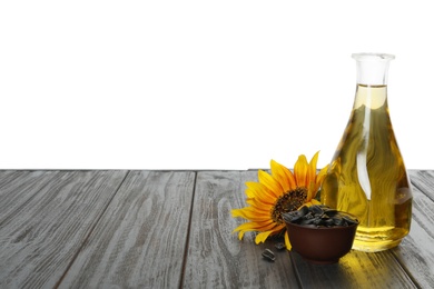 Sunflower, bottle of oil and seeds on black wooden table against white background, space for text Photo of Sunflower, bottle of oil and seeds on black wooden table against white background, space for text