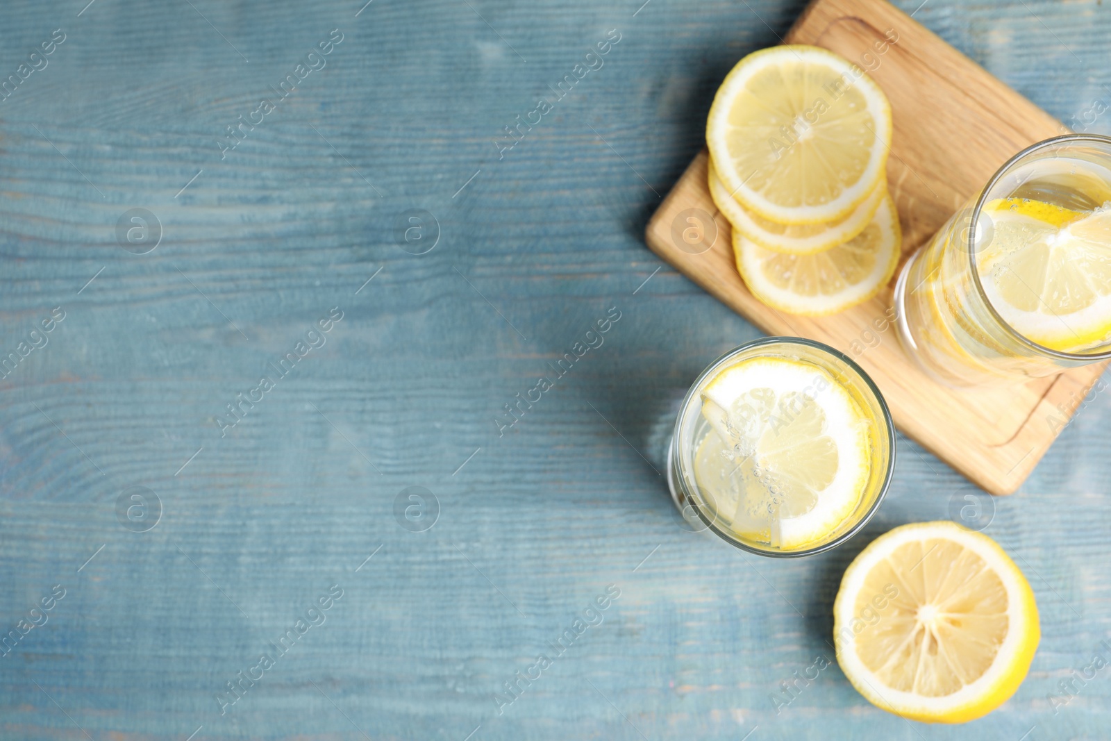 Soda water with lemon slices on blue wooden table, flat lay. Space for text Photo of Soda water with lemon slices on blue wooden table, flat lay. Space for text