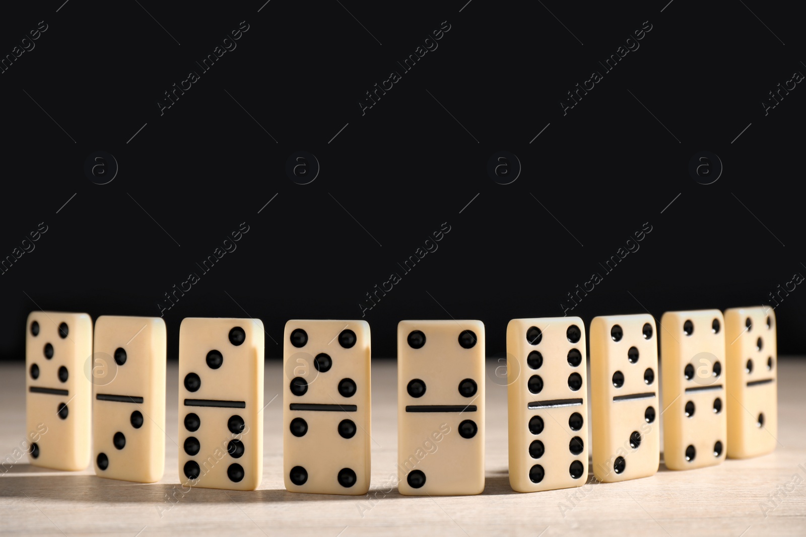 Domino tiles on wooden table against black background. Space for text Photo of Domino tiles on wooden table against black background. Space for text
