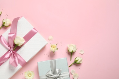 Elegant gift boxes and beautiful flowers on pink background, flat lay. Space for text Photo of Elegant gift boxes and beautiful flowers on pink background, flat lay. Space for text