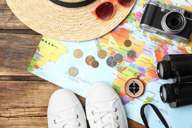 Photo of Flat lay composition with world map and different travel accessories on wooden table. Planning summer vacation trip