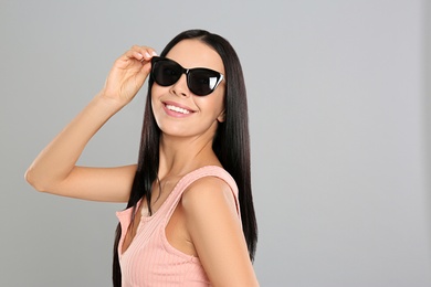 Beautiful woman wearing sunglasses on grey background Photo of Beautiful woman wearing sunglasses on grey background