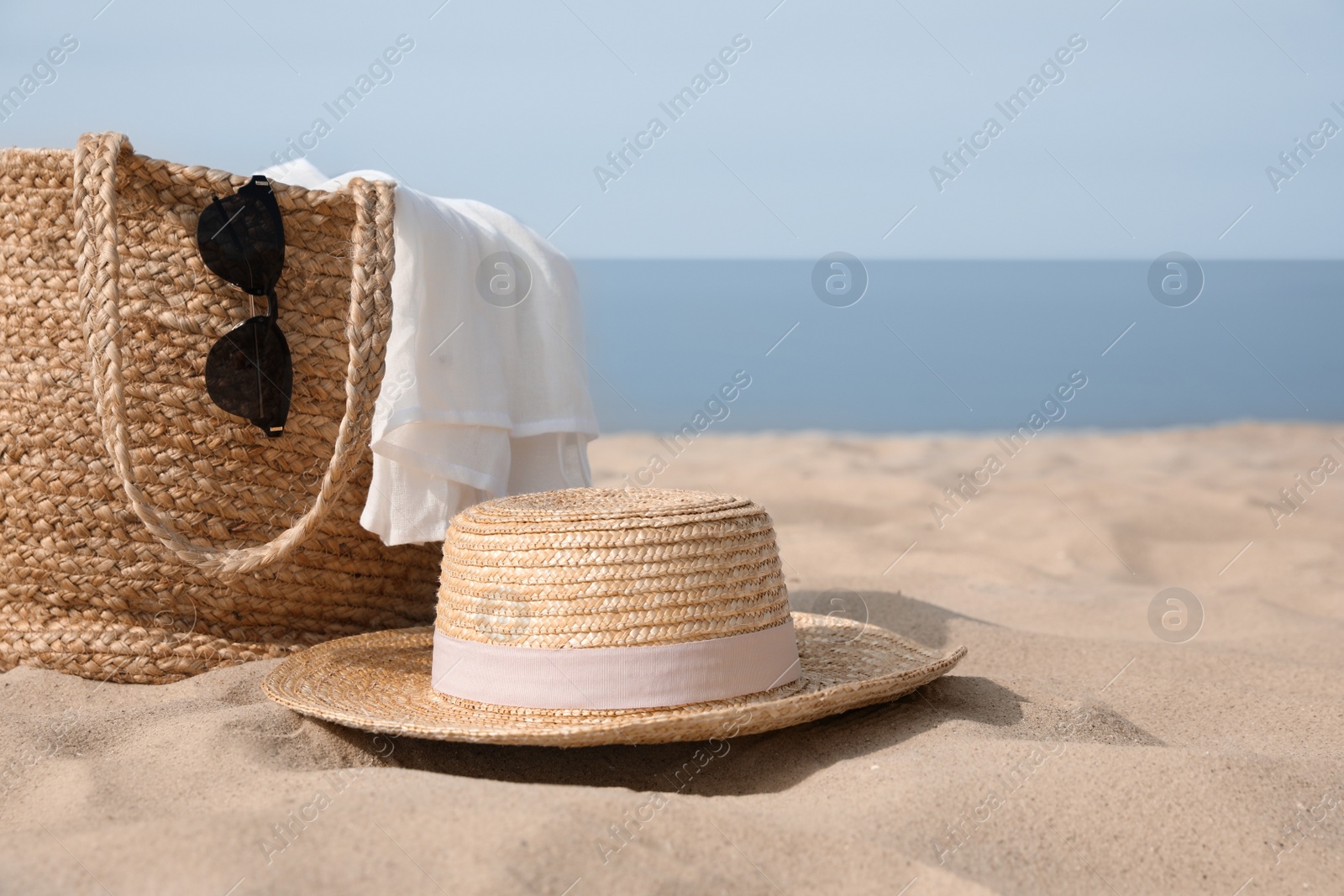 Beach bag, towel, sunglasses and hat on sandy seashore, space for text Photo of Beach bag, towel, sunglasses and hat on sandy seashore, space for text